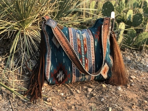 Detail of woven bohemian shoulder bag featuring leather tassels and antique metal buckle