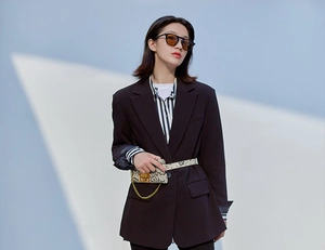 Detail view of round jelly-colored sunglasses paired with a chic blazer and snake skin bag