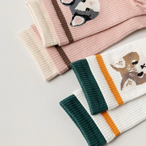 Detail of pink and white mid-calf socks with cute cartoon dogs and striped cuffs