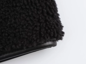 Gros plan détaillé sur le tissu imitation peau de mouton noire et liseré en cuir