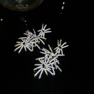 Macro shot of silver fireworks stud earrings with sparkling zircon on black background