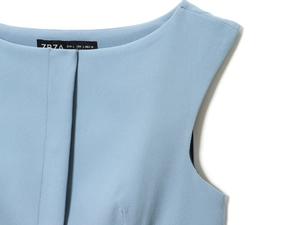 Dettaglio dello scollo di un top senza maniche azzurro con etichetta della taglia