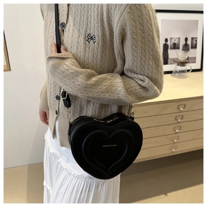 Fashionable heart-shaped black crossbody bag with gold hardware and embossed text detail