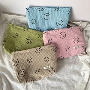 Detail of four colorful corduroy cosmetic bags with smiley face print and zipper