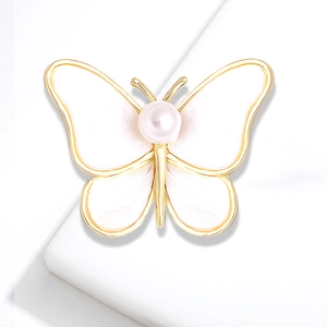Elegant gold butterfly brooch with white enamel wings and a centered pearl on white background