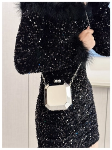 Detail of silver octagonal mirror clutch bag with metallic chain on black sequin dress
