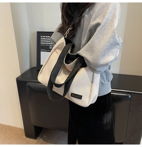 Close-up of cream canvas tote bag with black strap worn by model for daily commute