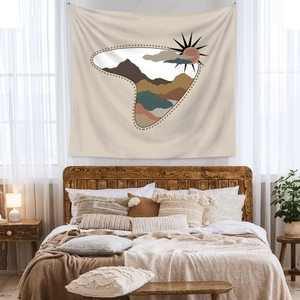Close-up of bohemian tapestry with sun and mountain patterns hanging above a cozy bed