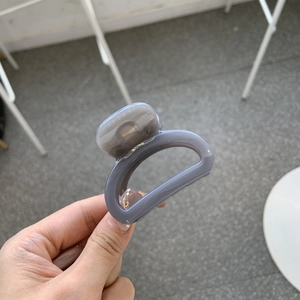 Close-up of a grey-purple glossy resin hair claw clip with durable metal spring held by hand