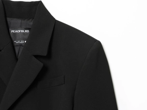 Détail du col du blazer et de la ligne d'épaule sur une veste de costume noire chic