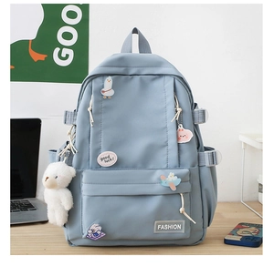 Dettaglio di zaino in nylon azzurro con simpatici badge e ciondolo a forma di orsetto