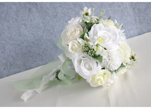 Close-up of artificial bridal bouquet with white roses, lace handle and green silk ribbon