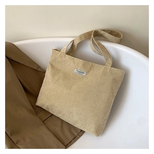 Close-up of khaki corduroy tote bag texture with wide shoulder straps and fashion label