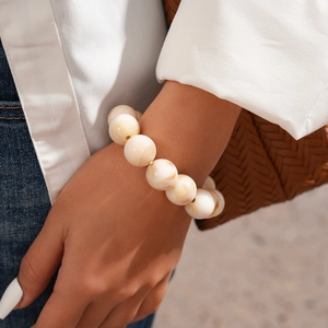Detail of beaded bracelet with cream marble acrylic beads worn against a white blazer