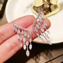 Detail of wing-shaped tassel earrings with silver finish and white zircon stones