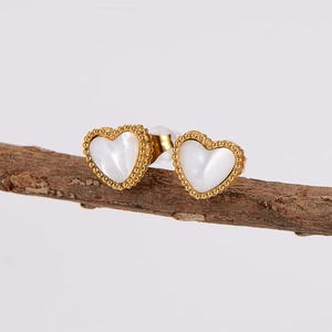 Golden heart earrings with white mother-of-pearl inlay and beaded edges on wood branch