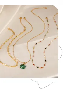 Detail of layered gold titanium steel necklaces with natural stones and paperclip chain links