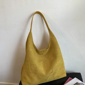 Minimalist yellow suede HOBO shoulder bag for women leaning against a white textured wall