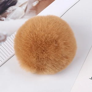 Close-up of 8cm tan faux rabbit fur pom pom with soft fluffy texture on white background