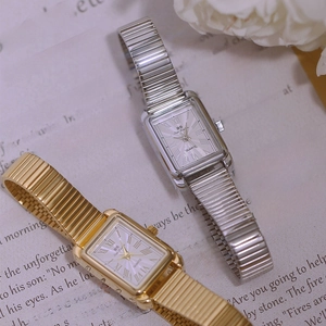 Detail of gold and silver square quartz watches with elastic bands on book pages