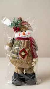 Detail view of a snowman plush doll with green plaid coat and red scarf for Christmas