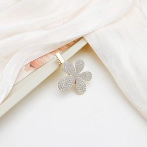Detailed macro view of a sparkling floral hair clip with rhinestones on white silk fabric