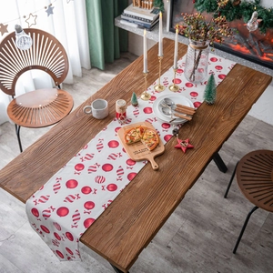 Christmas table runner with red candy cane and bauble print on rustic wooden table