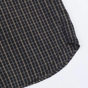Close-up of dark plaid shirt hem showing detailed woven texture on white background
