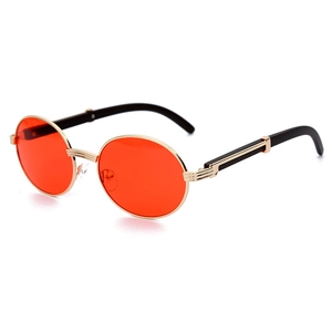 Gafas de sol ovaladas retro con lentes rojas y montura dorada mostradas en ángulo de 45°