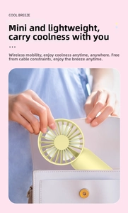 Mini handheld cooling fan in yellow being placed into a small white shoulder bag
