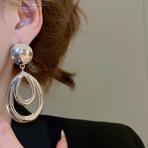 Vue détaillée de grandes boucles d'oreilles goutte argentées portées par un mannequin