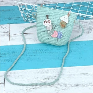 Close-up of mint green woven crossbody bag with cartoon mushroom and caterpillar patches