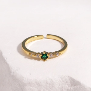 Close-up of adjustable gold-plated ring featuring an emerald green zircon center stone