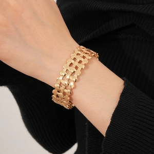 Detailed view of wide gold layered oval hollow cuff bracelet worn on a model's wrist
