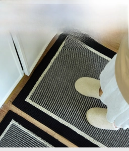 Detail of black and white striped kitchen mat with 3D woven texture on wood floor