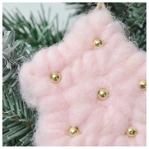 Close-up of pink plush star ornament with gold beads on green Christmas tree branch