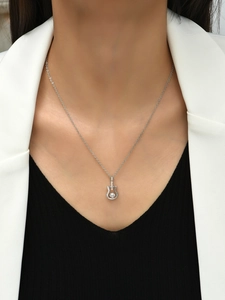 Silver guitar necklace with a large clear zircon stone, worn on a stylish model