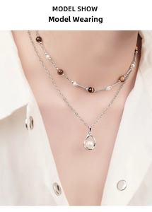 Detail of layered 925 silver necklace with tiger eye beads and a pearl drop pendant