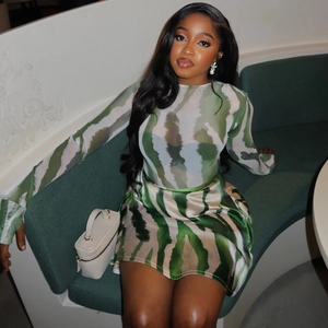 Detailed view of green and white abstract print mesh top and satin skirt on a sofa