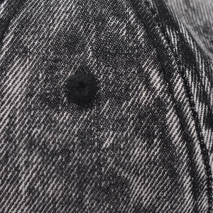 Macro shot of washed denim fabric texture with a stitched ventilation eyelet on a baseball cap