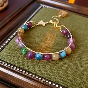 Detail of beaded bracelet with tiger eye stones and golden wire wrap on velvet