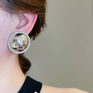 Macro view of oversized silver dome earrings with sparkling rhinestone trim on model