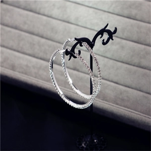 Macro shot of oversized silver hoop earrings with shimmering crystal rhinestones on a stand
