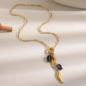 18K gold plated paperclip necklace with cascading fish charms on a beige textured surface