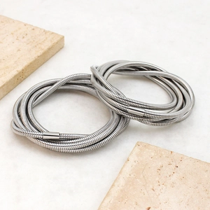 Detailed view of layered silver stainless steel snake bone bracelets on stone