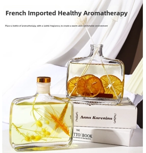 Detail of reed diffuser with dried orange, cinnamon sticks and grass in square glass bottle
