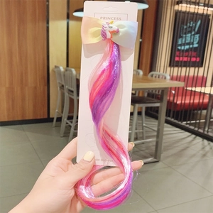 Hand holding unicorn rainbow bow hair clip with colorful hair extension for kids