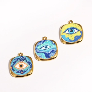 Detailed macro of three gold-plated square pendants with colorful oil-painted evil eyes