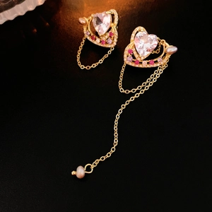 Détail de boucles d'oreilles cœur doré avec glands en zircon et perles d'eau douce