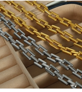 Macro shot of gold and silver paperclip chain links on a beige velvet jewelry display